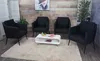 A waiting area with four black armchairs and a white coffee table with magazines on it. Produktbild-Vorschau