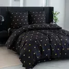 A neatly made bed with black bedding adorned with small golden hearts. Produktbild-Vorschau