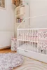 A nursery room with a crib, bookshelf, and rug. Produktbild-Vorschau