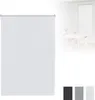 A white roller blind is shown in the foreground, with a blurred background depicting a dining room setting with a table and chairs.