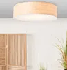 A ceiling light with a bamboo shade and white diffuser is shown against a white brick wall.