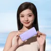 A woman is holding a purple power bank in front of a light blue and white background. Produktbild-Vorschau