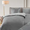 A bed with gray bedding and pillows, next to a floor lamp. Produktbild-Vorschau