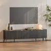 A modern media console with a television mounted above it, set in a well-lit room with a plant. Podgląd zdjęcia produktu