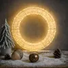 A lit LED wreath is displayed on a surface covered in artificial snow, with a small frosted Christmas tree and decorative acorns and pinecones. Produktbild-Vorschau