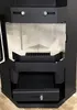 Close-up view of the interior of a black corner fireplace, showing the fire grate, ash pan, and drawers. Anteprima dell’immagine prodotto