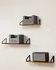 Three shelves are mounted on a white wall, each displaying an item. The top two shelves hold identical grey weight plates labeled '10 kg'. The bottom shelf has a black and silver speaker. Náhled obrázku produktu