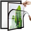 Hands are holding a magnetic frame with a diamond painting of cacti inside, showing how it is placed into a larger black frame. Podgląd zdjęcia produktu