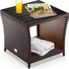 A brown polyrattan side table with a black WPC tabletop, a glass of orange juice, and two magazines on top. A folded white towel is on the lower shelf. Anteprima dell’immagine prodotto