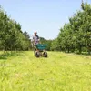 A person is using a spreader in a grassy area with trees. Produktbild-Vorschau