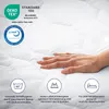 A hand resting on a white quilted mattress topper, with various certification logos and feature icons displayed around it. Produktbild-Vorschau