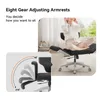 A person is sitting on an office chair with their legs crossed, and a diagram shows the adjustable armrests of the chair. Podgląd zdjęcia produktu