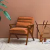 A stylish armchair in a warm, earthy-toned room with decorative elements. Produktbild-Vorschau