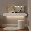 A modern white vanity table with a lighted mirror, makeup, and a stool. Produktbild-Vorschau