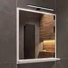 A bathroom mirror with a shelf and LED light mounted on a tiled wall. Náhled obrázku produktu