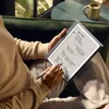 A person is using a Kindle Scribe e-reader while sitting on a couch. Náhľad obrázku produktu