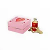 A pink gift box with a heart cutout and a red perfume bottle on a gold heart-shaped stand. Voir les images du produit