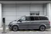 A grey electric vehicle is plugged into a charging station in front of a modern building. Produktbild-Vorschau