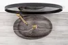A top-down view of a stone sink with a gold faucet and drain, set against a light wooden surface, with a dark framed mirror reflected above. Produktbild-Vorschau