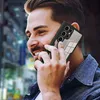 A man is on a phone call, holding a smartphone with a protective case. Produktbild-Vorschau