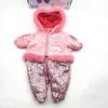 A pink winter snowsuit for a doll is laid out flat against a white background. The snowsuit has a fur-lined hood and cuffs, and the pants are covered in sequins. Produktbild-Vorschau