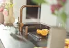 A kitchen counter with a copper faucet and soap dispenser, next to a sink with sliced oranges. Podgląd zdjęcia produktu