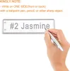 A hand is shown writing on a metal plant tag with the name "#2 Jasmine" embossed on it. The text above provides instructions on how to write on the tags. Produktbild-Vorschau