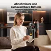 A woman is holding a cordless vacuum cleaner and its detachable battery in a modern kitchen setting. Produktbild-Vorschau