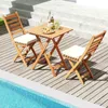 A wooden bistro set with two chairs and cushions is placed on a wooden deck next to a swimming pool. Anteprima dell’immagine prodotto