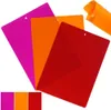 Three flexible cutting mats in pink, orange, and red are fanned out against a white background. A rolled-up orange mat is visible in the upper right corner. A smaller inset shows the three mats side-by-side. Voir les images du produit
