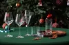 A collection of glassware arranged on a green tablecloth in front of a decorated Christmas tree. Produktbild-Vorschau