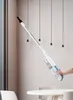 A hand holding a vacuum cleaner in a modern room with hanging lights. Náhled obrázku produktu