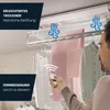 A man is using a remote control to operate a ceiling-mounted electric clothes dryer with laundry hanging on it. Produktbild-Vorschau