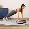 A woman is doing a plank exercise on a vibration plate in a room. Náhled obrázku produktu