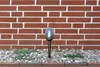 A solar garden light is placed in a gravel bed in front of a brick wall. Anteprima dell’immagine prodotto