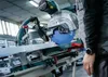 A person using a miter saw in a workshop. Voir les images du produit