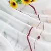 A close-up view of a sheer curtain with a floral pattern and embroidered trim. Produktbild-Vorschau