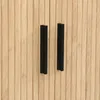 A close-up view of two black handles on a wooden cabinet. Anteprima dell’immagine prodotto