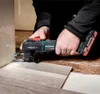 A person is using a Metabo multitool to cut flooring near a wall. Náhľad obrázku produktu