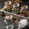 A close-up shot of several Kilner spice jars with flip-top lids, some filled with spices and herbs, arranged in a wooden tray. Two empty jars are in the foreground. Anteprima dell’immagine prodotto