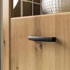 A close-up of a wooden cabinet door with a black handle. Produktbild-Vorschau