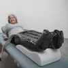A woman is lying on a medical table with compression boots on her legs. Produktbild-Vorschau