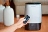 A hand holding a remote control is shown in the foreground, with a Blaupunkt ultrasonic humidifier in the background. Produktbild-Vorschau