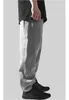 A person wearing grey sweatpants and black shoes, shown from the side. Produktbild-Vorschau