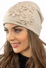 A woman wearing a beige winter hat with flower appliqués. Náhled obrázku produktu