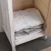 Folded clothes are neatly stacked on a shelf inside a wooden cabinet. Náhľad obrázku produktu