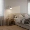 A bedroom scene with a bed, nightstand, and a wall lamp. Náhled obrázku produktu