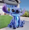 A large Stitch figurine is sitting on a patio next to a lawn. Produktbild-Vorschau