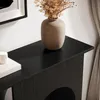 A close-up view of the top surface of a black console table, featuring a vase with dried flowers and a stack of books. Produktbild-Vorschau