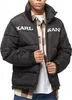 A person wearing a black puffer jacket with white text on it. Voir les images du produit